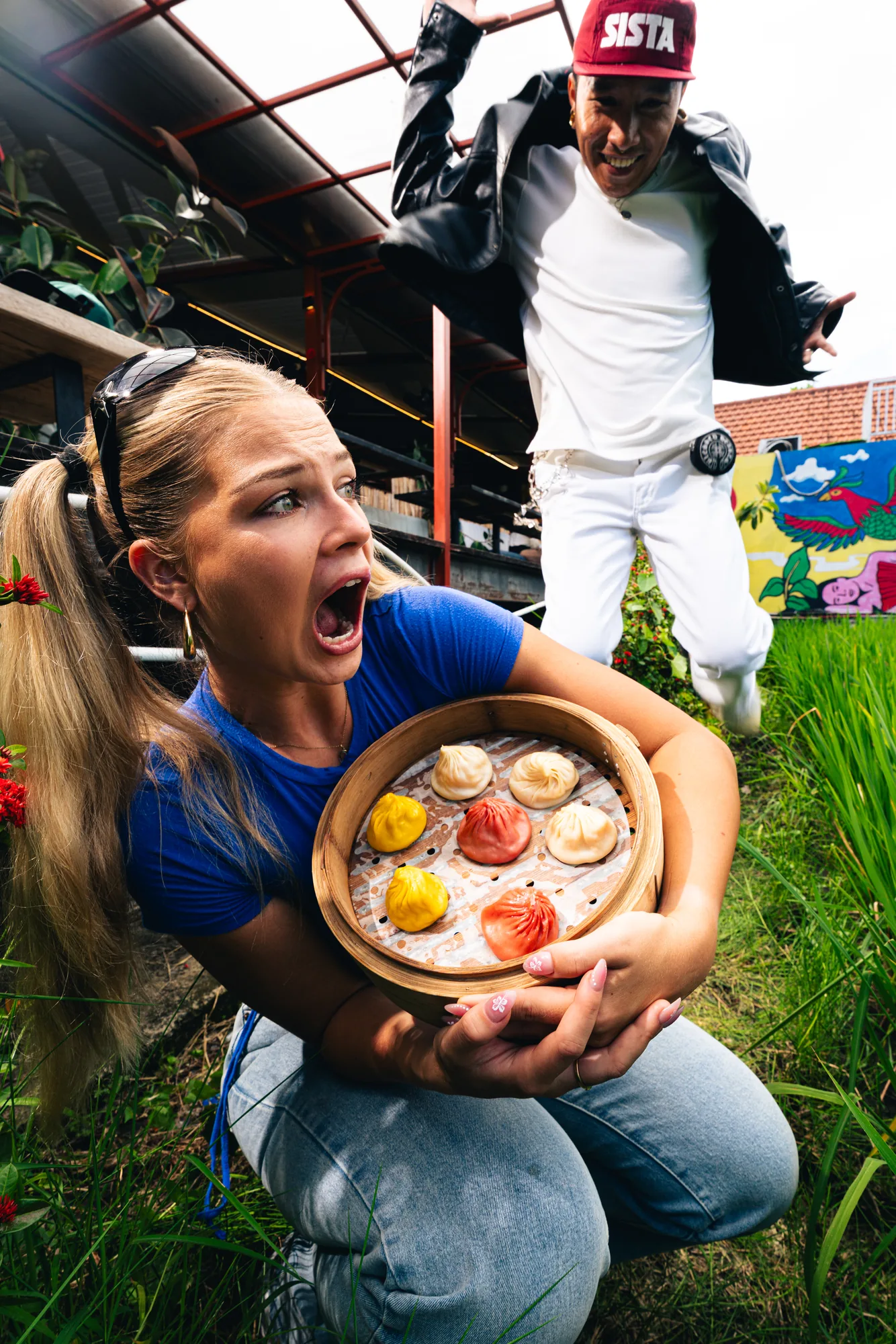 Guest holding a bamboo steamer of dumplings with a friend behind