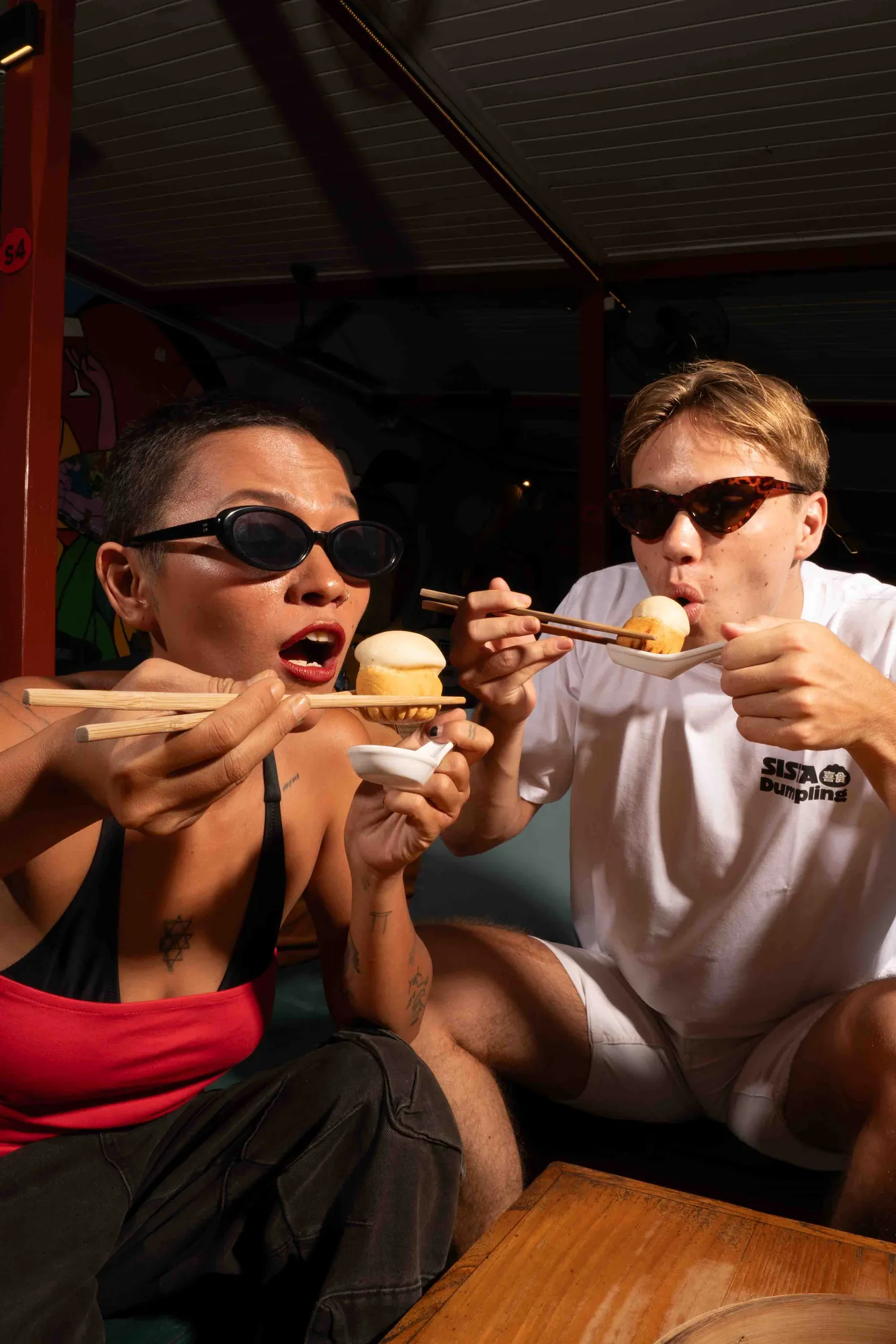 Two friends eating dumplings together inside Sista