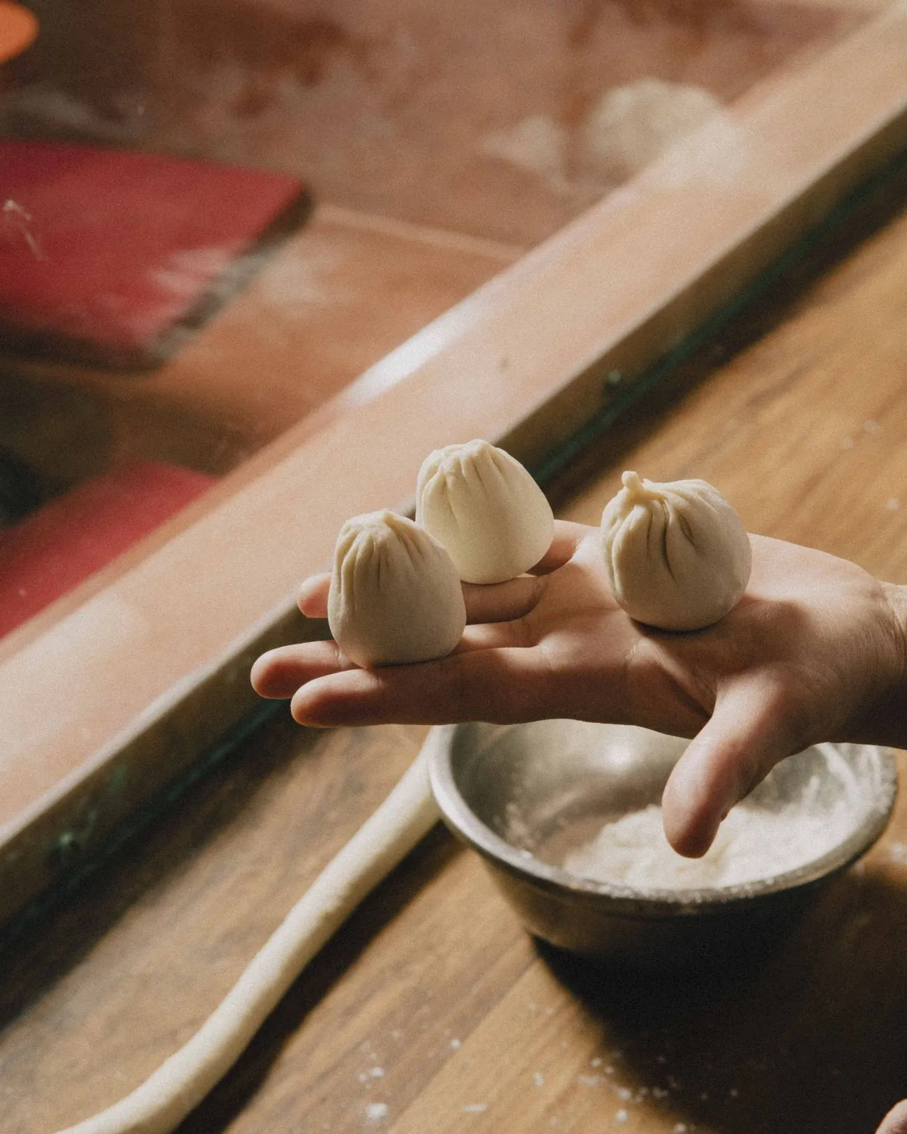 Hands folding a fresh dumpling, dusted with flour