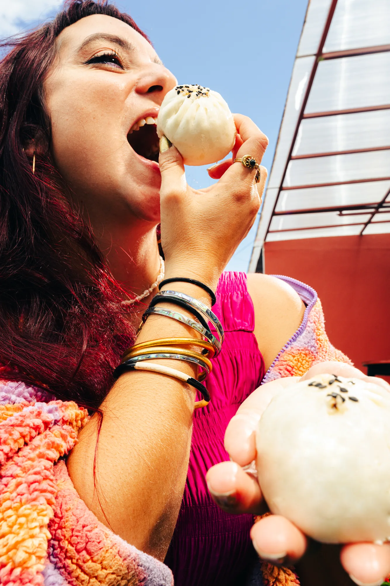 Guest biting into a steamed bao bun against a red backdrop