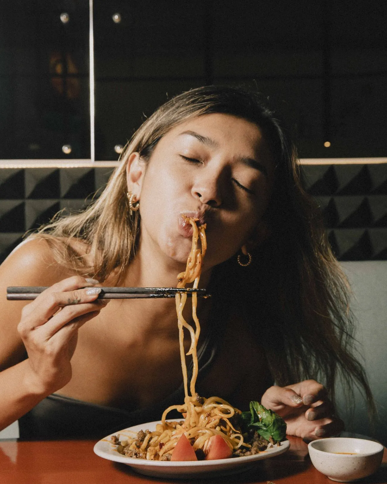 Chilli oil being poured over hand-pulled noodles with peanuts and scallion