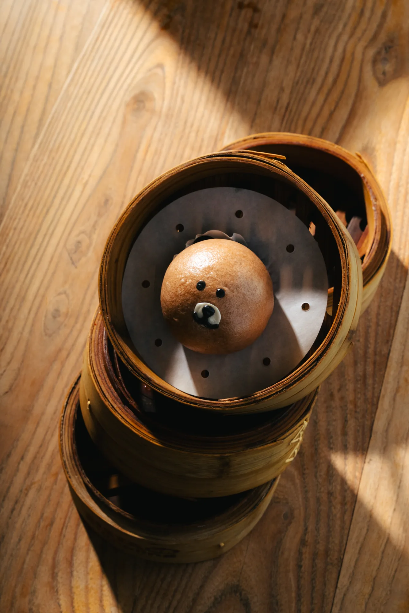 Bamboo steamer with a freshly steamed dumpling on a wooden table